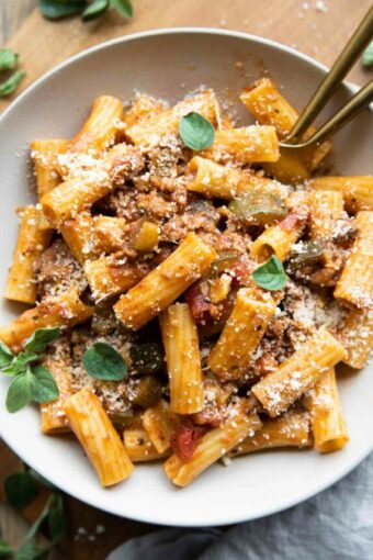 The BEST Rigatoni Bolognese recipe in a bowl with oregano and parmesan.