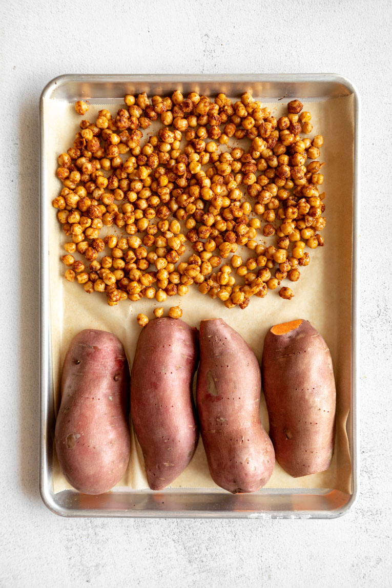 Chickpeas and sweet potato halves on a baking sheet.