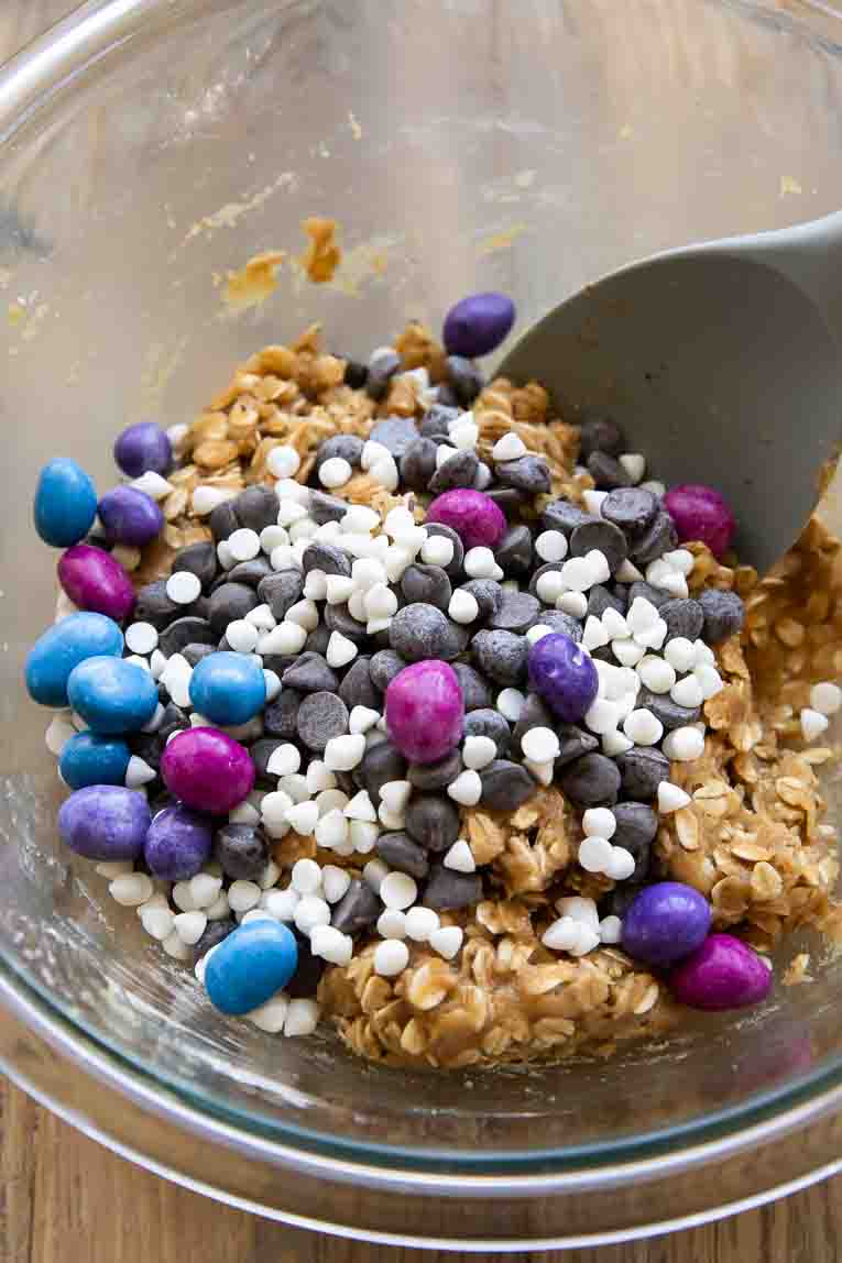 Candy and chocolate chips in cookie dough being mixed.