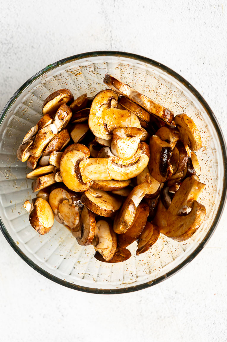 Mushrooms being marinated in a bowl.