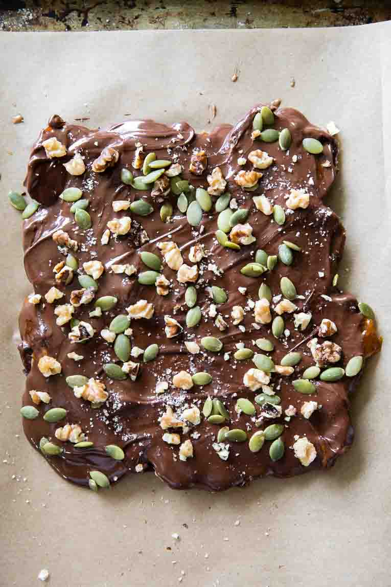 Melted chocolate over pumpkin date bark with toppings.