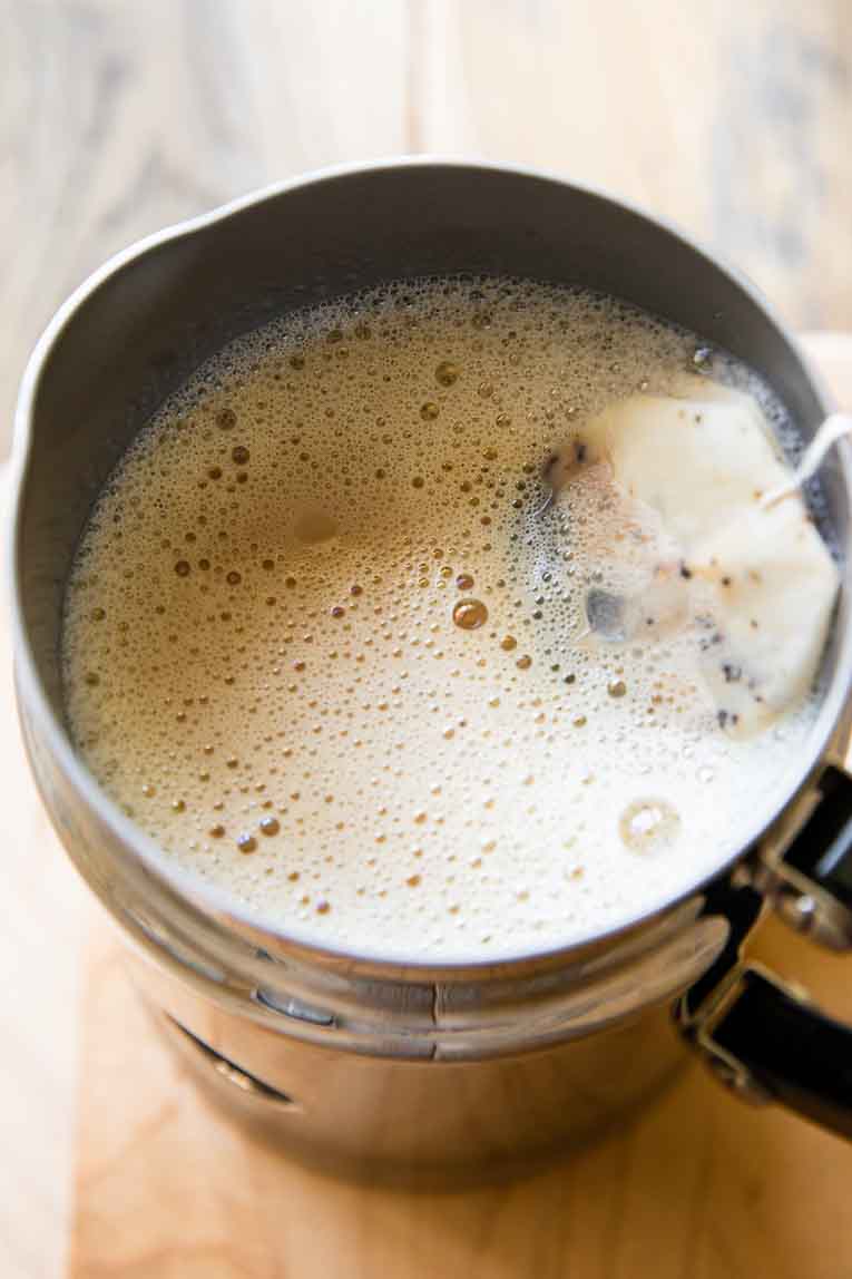 Chai tea being steeped with frothy milk.