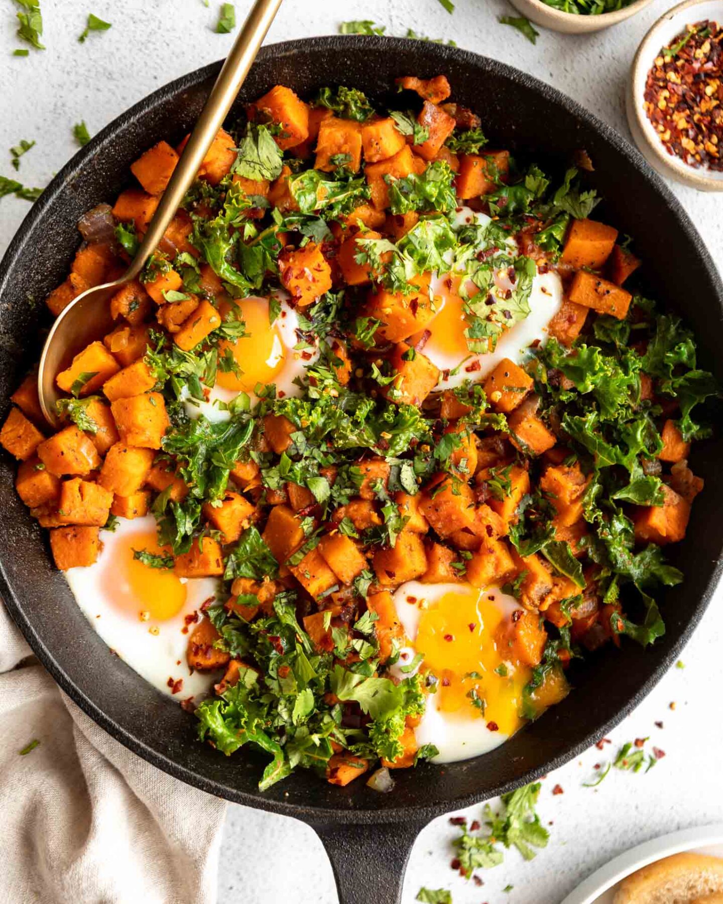 Skillet Sweet Potato Kale Hash recipe in a cast iron skillet with eggs.
