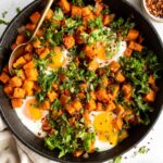 Skillet Sweet Potato Kale Hash recipe in a cast iron skillet with eggs.
