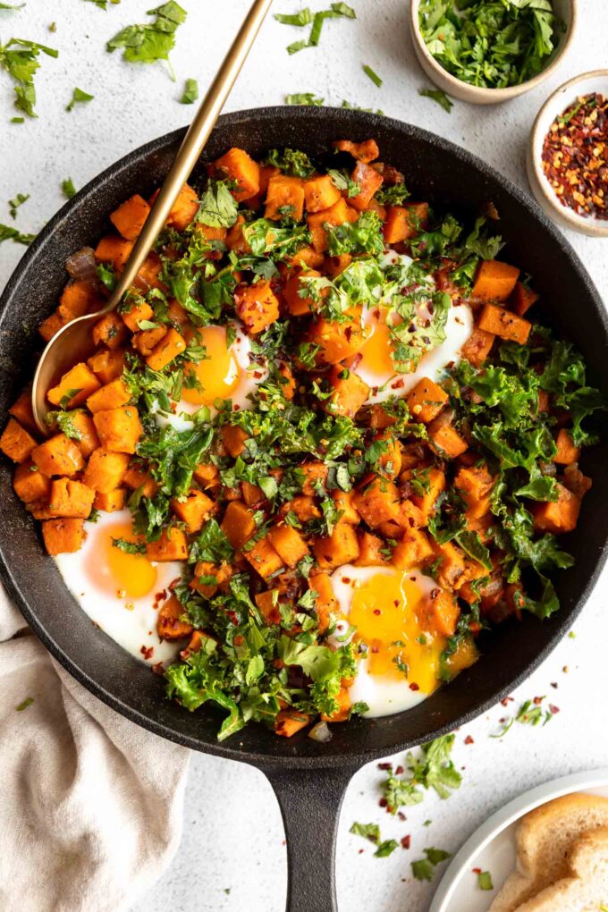 Skillet Sweet Potato Kale Hash recipe in a cast iron skillet with eggs.