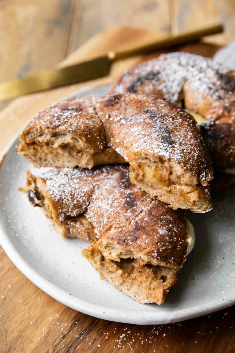 Stacked Cinnamon Raisin Bagel French Toast Sandwiches with powdered sugar.