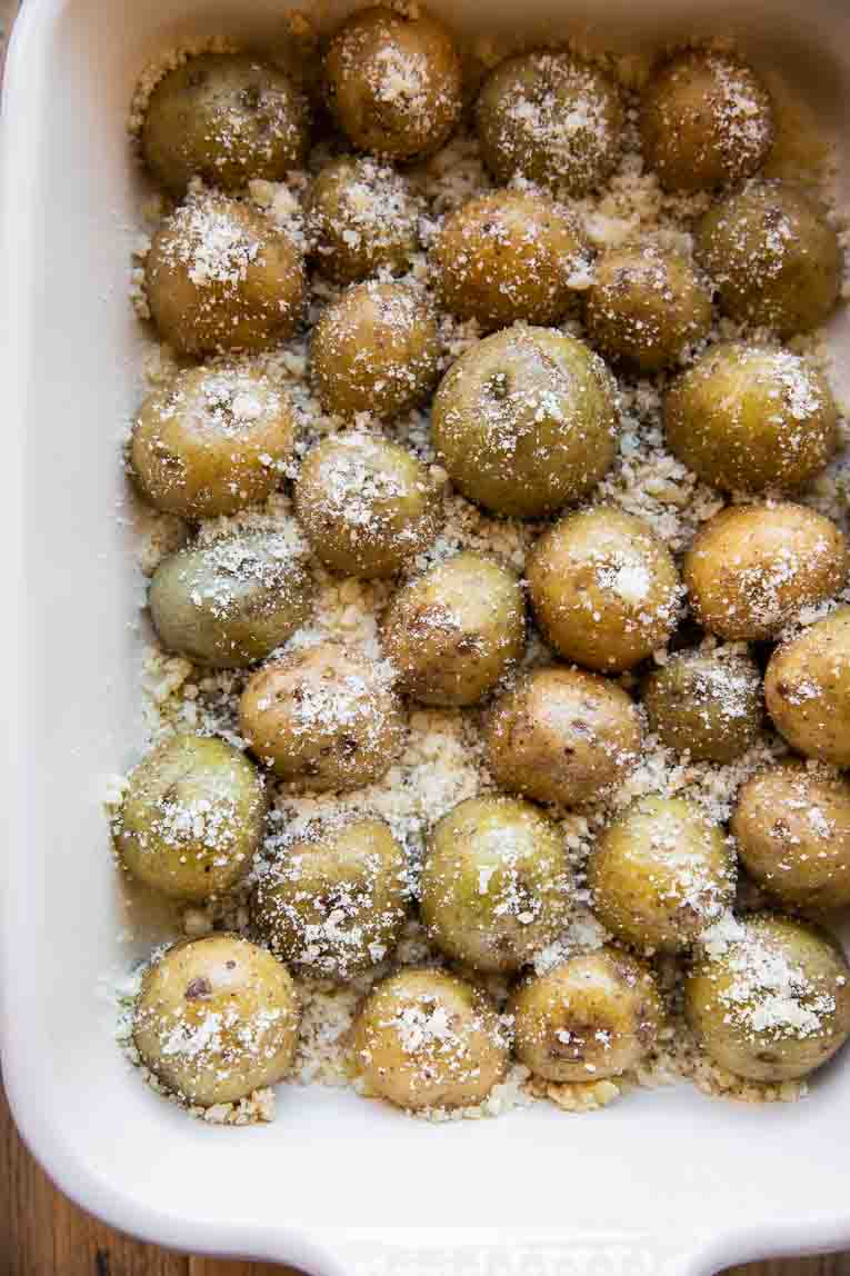 Halved small potatoes in a baking dish with parmesan.