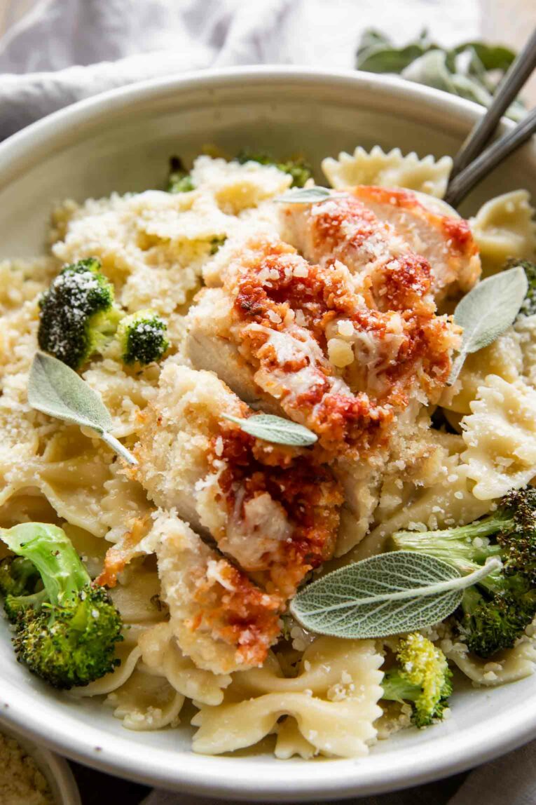 Angled close up of parmesan chicken over creamy garlic pasta.