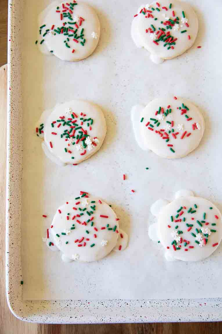 Gluten-Free Christmas Sugar Cookies dipped into icing and topped with sprinkles.