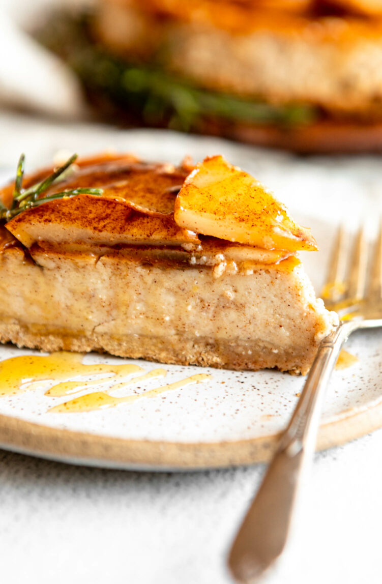 Close up of Honey Pear Ginger Cheesecake slice on a plate with rosemary.