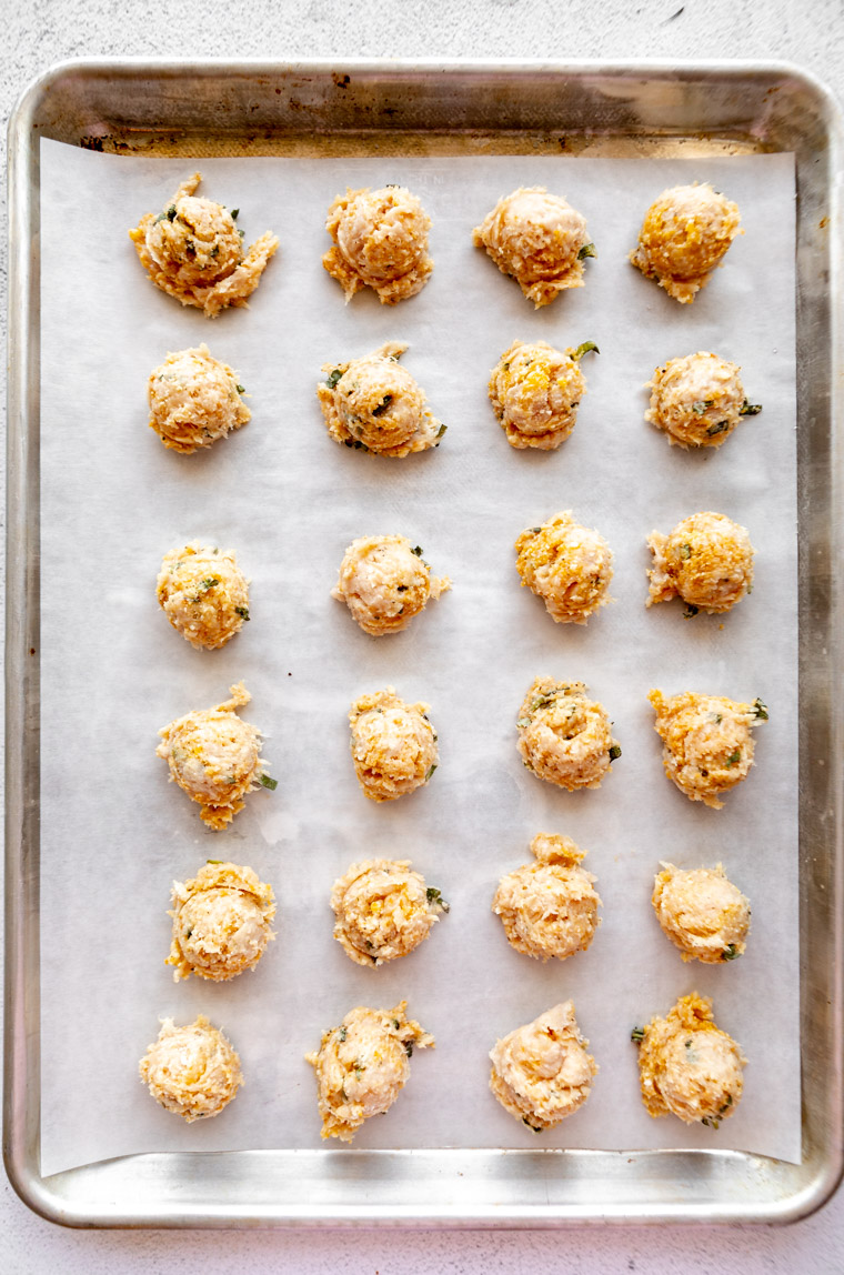 Turkey sage meatballs layer out on a baking sheet.