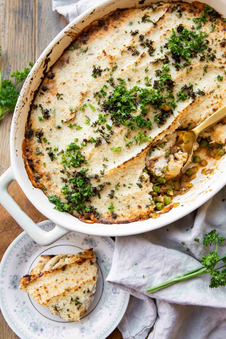 Vegetarian Shepherd's Pie in a casserole dish being spooned on to a plate.