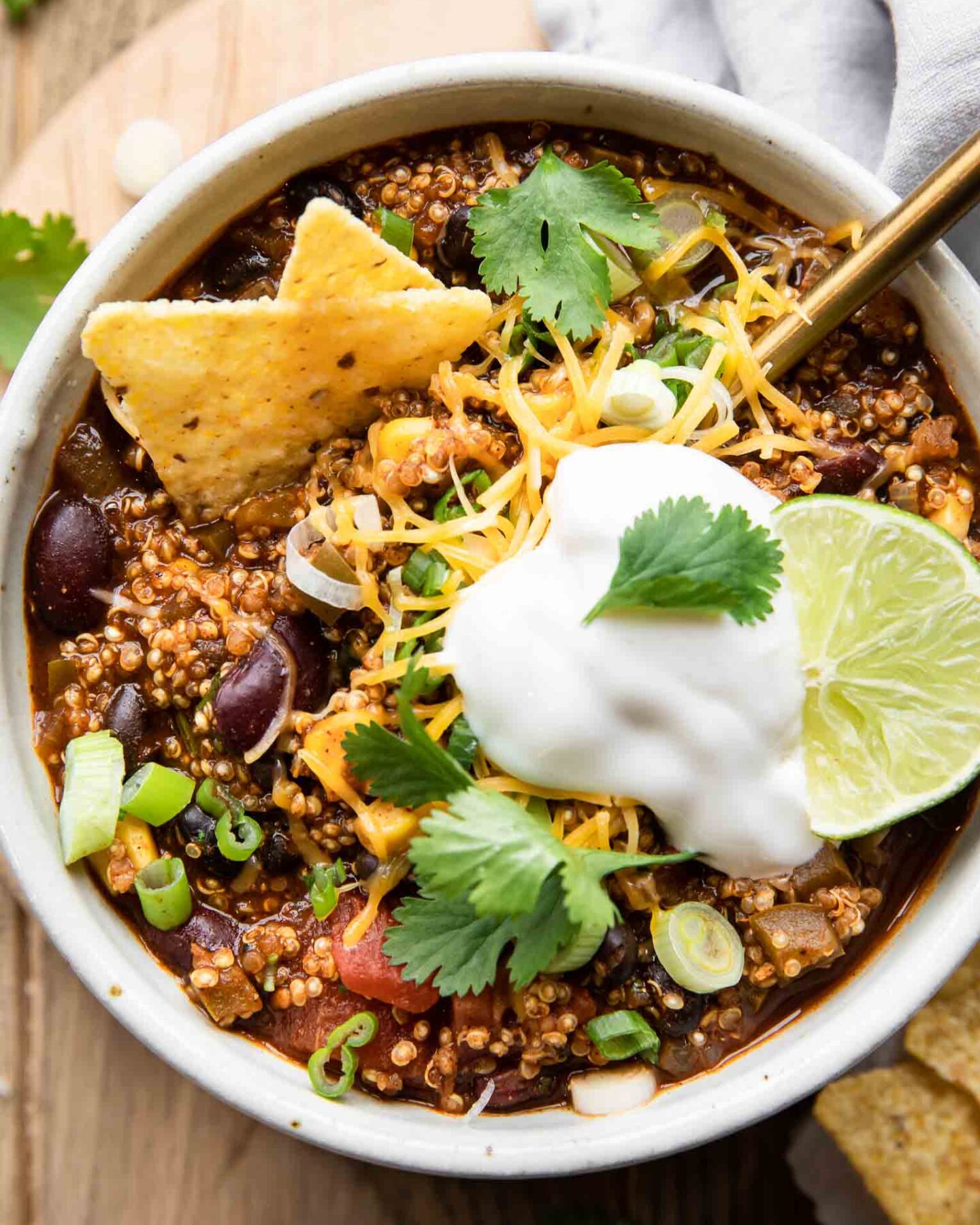 Easy Quinoa Chili recipe in a bowl with vegan sour cream, cilantro, lime, and chips.
