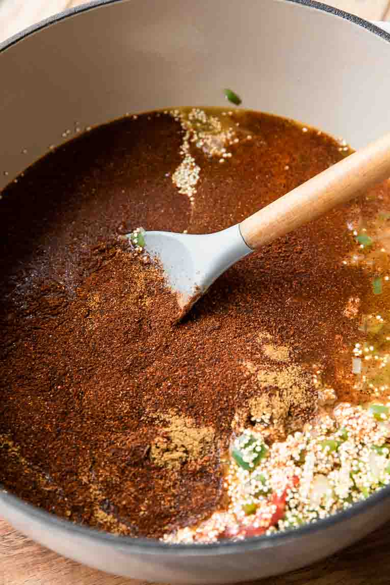 Ingredients for quinoa chili being mixed in a dutch oven.