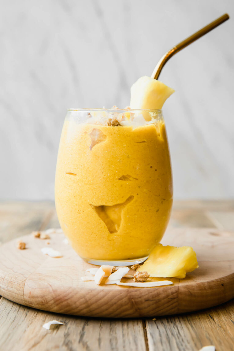 Golden Glow Pineapple Turmeric Smoothie with a pineapple garnish and straw.