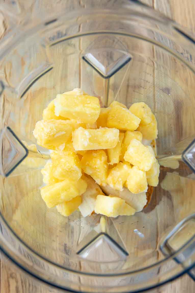 Pineapple chunks and coconut milk with ginger, turmeric, and banana in a blender.