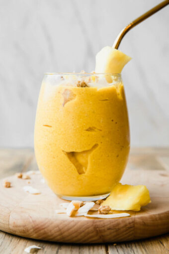Golden Glow Pineapple Turmeric Smoothie with a pineapple garnish and straw.