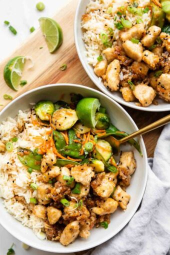 Two Honey Sesame Chicken Meal Prep Bowls with a fork.