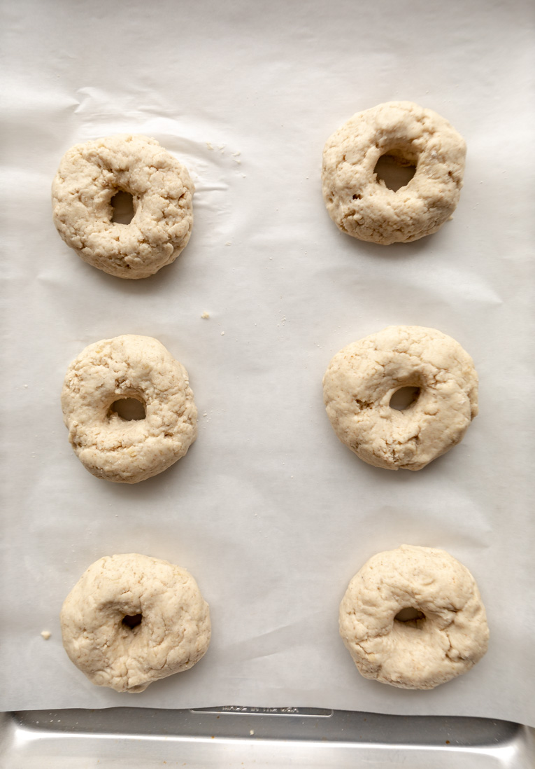 Gluten-free bagels on parchment paper after boiling.