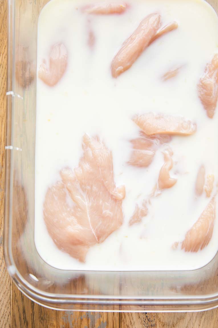 Chicken breasts being marinated in pickle juice and milk.
