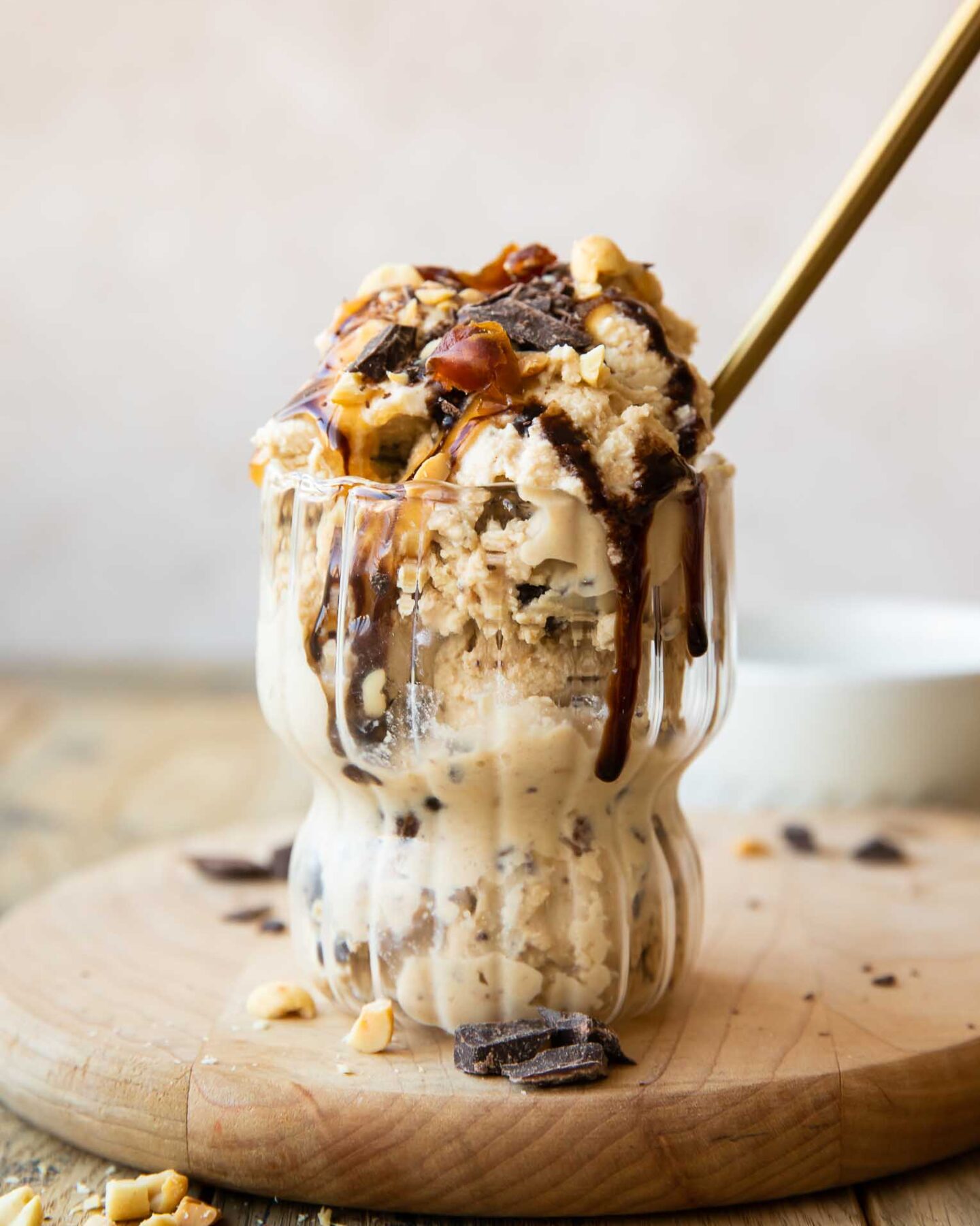 Ninja Creami Snickers Protein Ice Cream in a glass with toppings and a spoon.