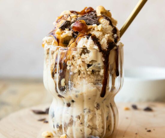 Ninja Creami Snickers Protein Ice Cream in a glass with toppings and a spoon.