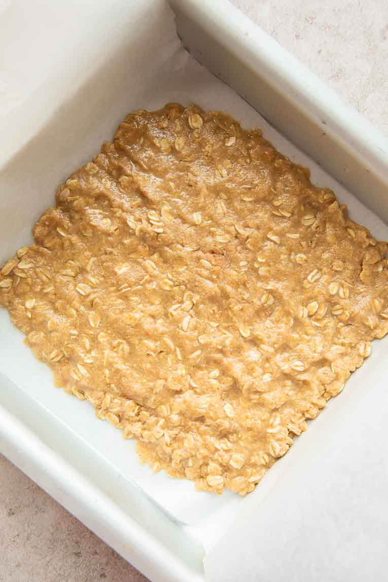 Oatmeal bar crust pressed into pan.