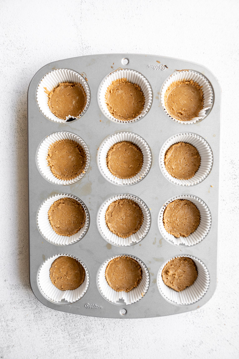 Graham cracker crusts pressed into a muffin tin.
