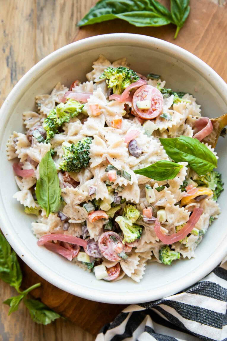 Creamy Vegan Pasta Salad recipe in a white bowl with fresh basil.