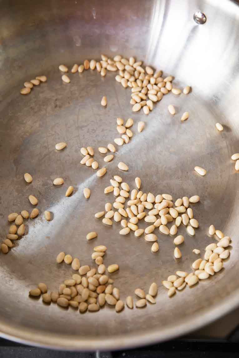 Pine nuts being toasted in a skillet.