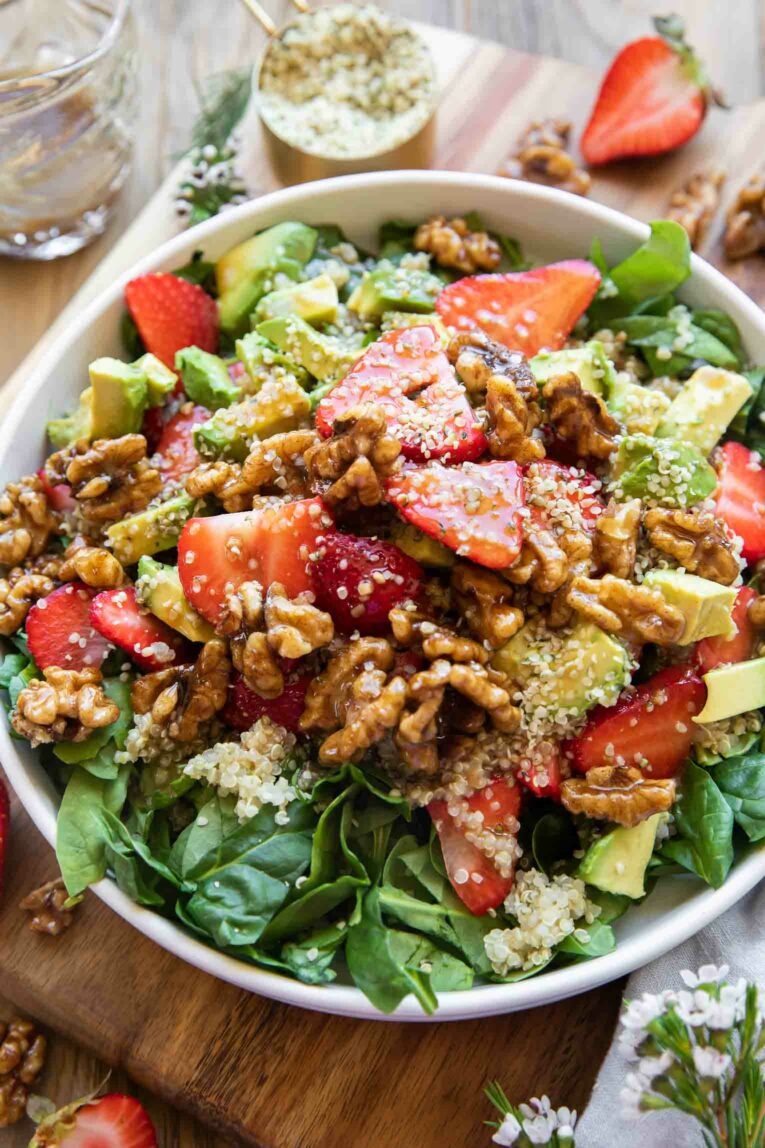 Angled photo of strawberries, spinach, and avocado with walnuts and hemp seeds.