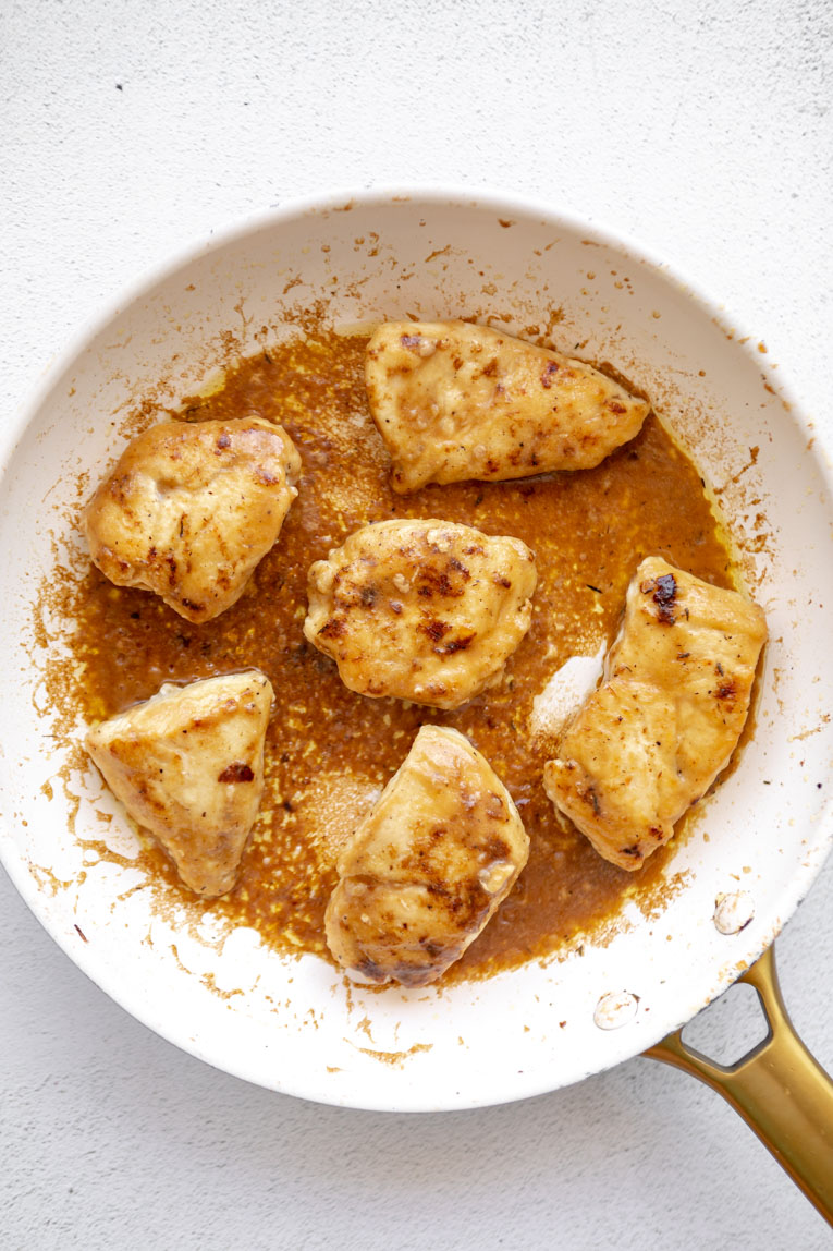 Sauce over French Onion Chicken being cooked in a skillet.