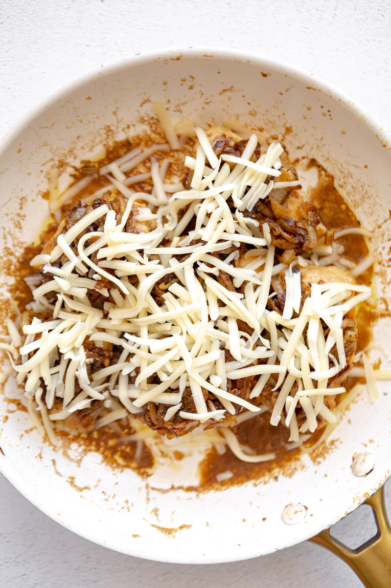 Cheese over french onion chicken in a pan.