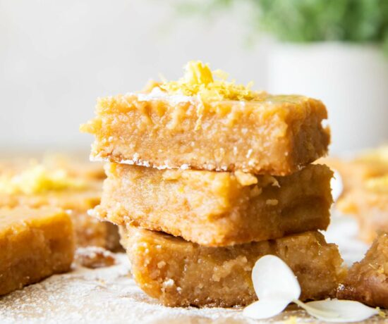 Gluten-Free Lemon Bars stacked with lemon zest on top.