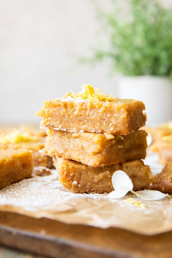 Gluten-Free Lemon Bars stacked with lemon zest on top.