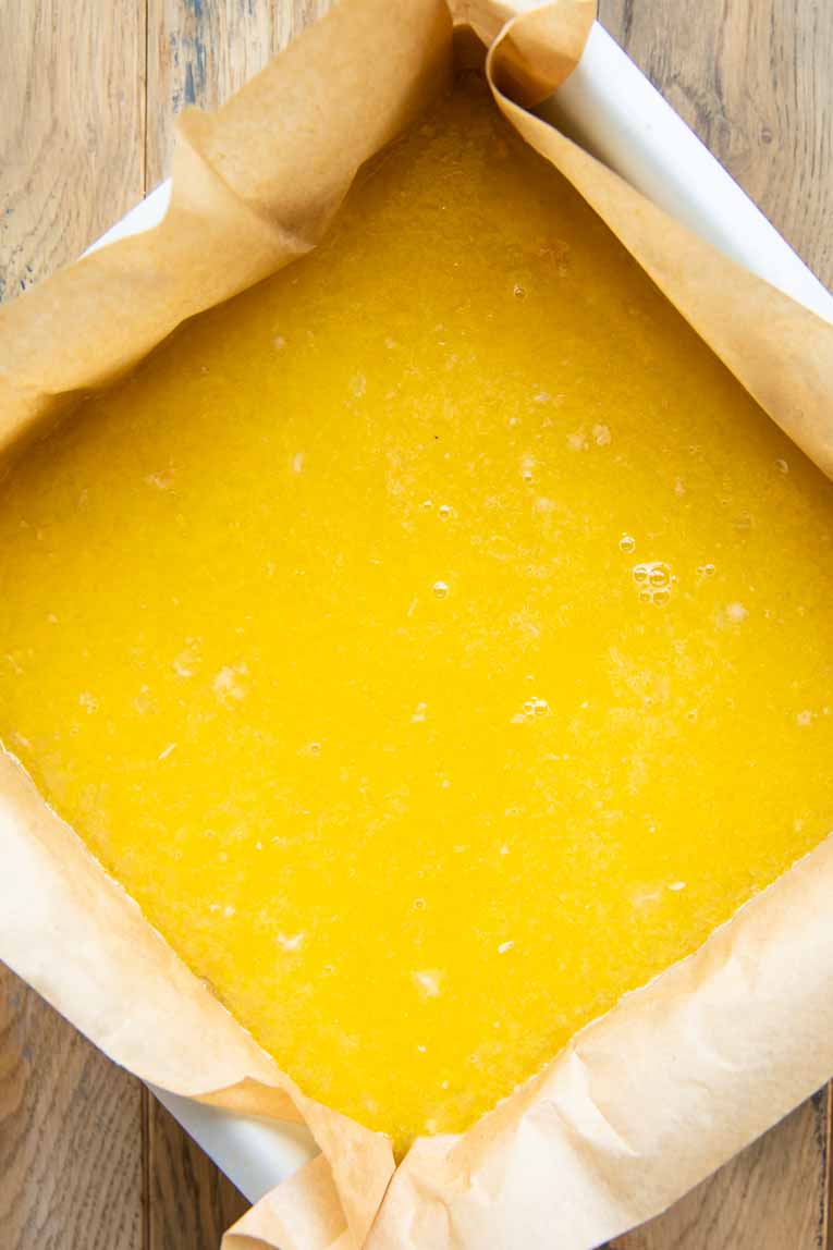 Lemon curd filling over shortbread crust in baking pan.
