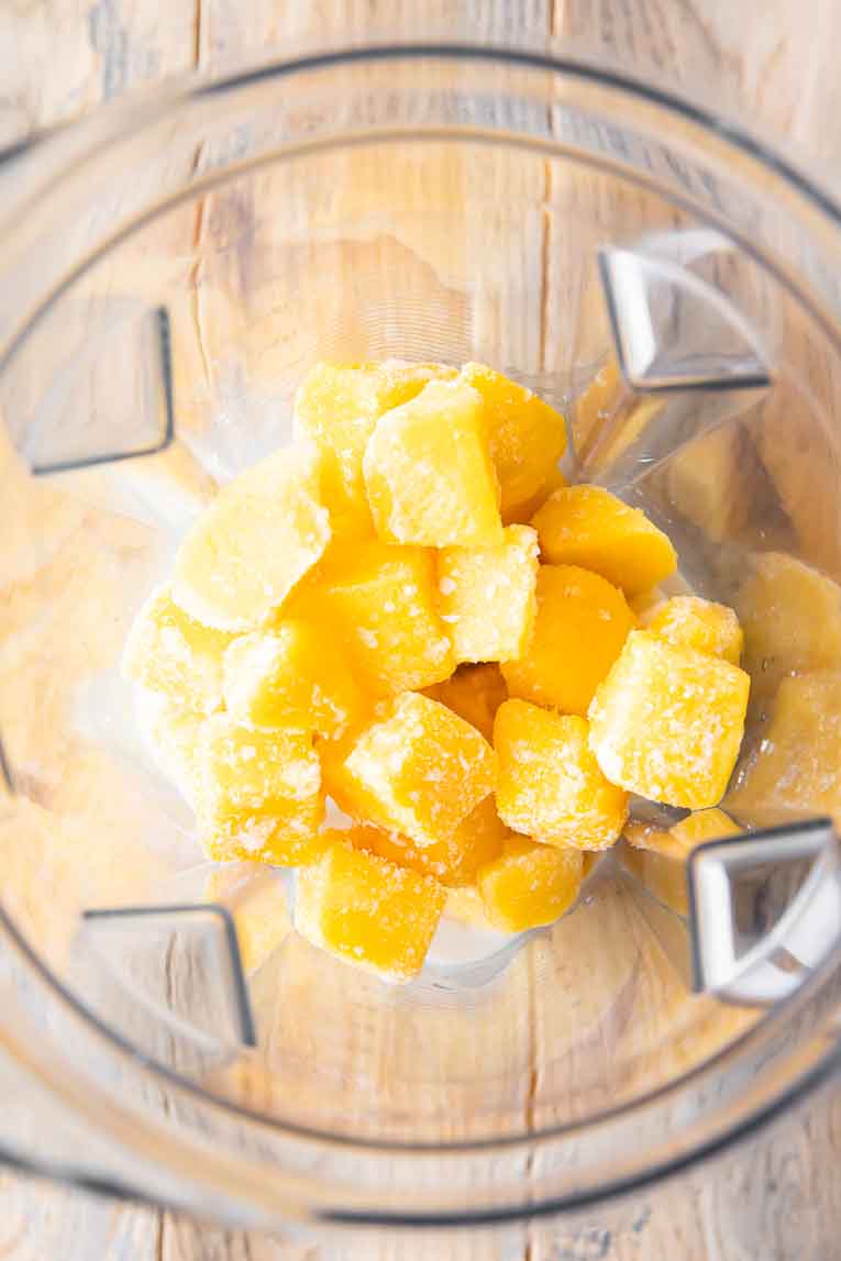 Top shot of mango banana smoothie ingredients in a blender.