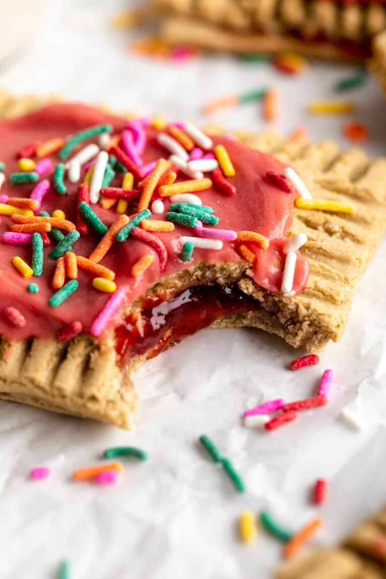 Angled close up of a Protein Pop Tart with strawberry icing and bite taken out.