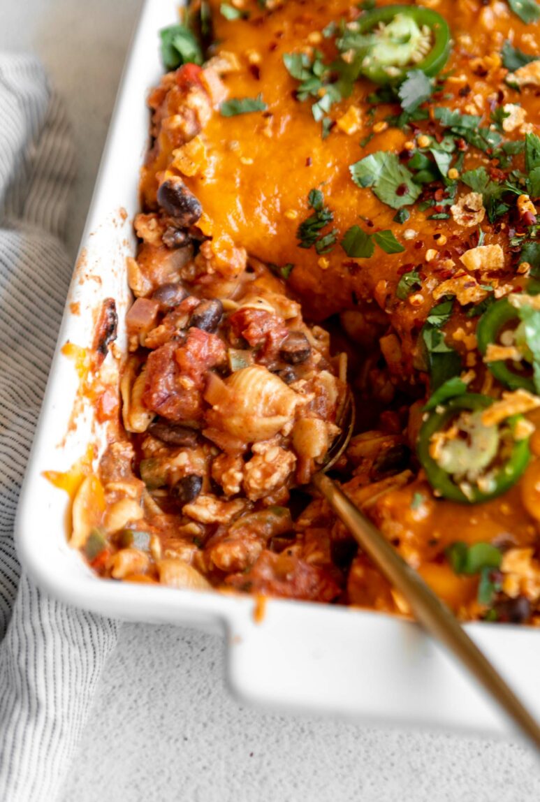 Angled photo of taco pasta casserole recipe in a casserole dish with a scoop taken out.