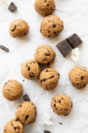 Chocolate Chip Cookie Dough Energy Bites on parchment paper with chocolate chunks.