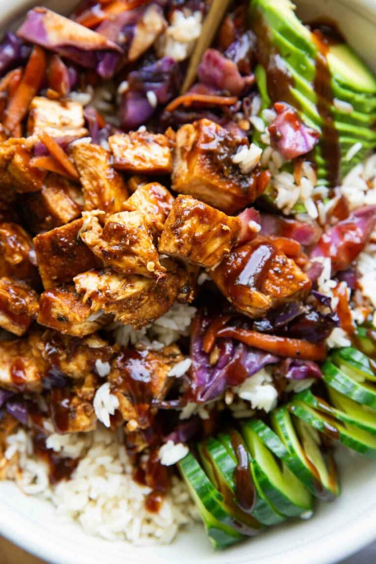 Close up of barbecue chicken over rice and vegetables.