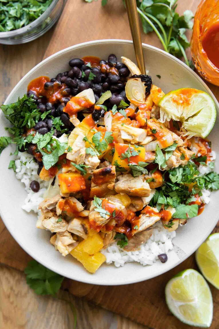 Top shot of Chicken Al Pastor Bowls with cilantro, lime, beans, and rice.