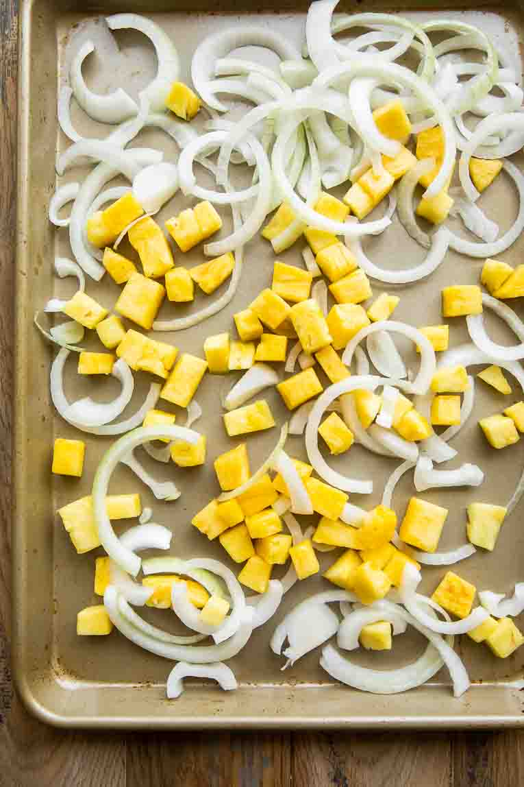 Onions and pineapple on a baking sheet.