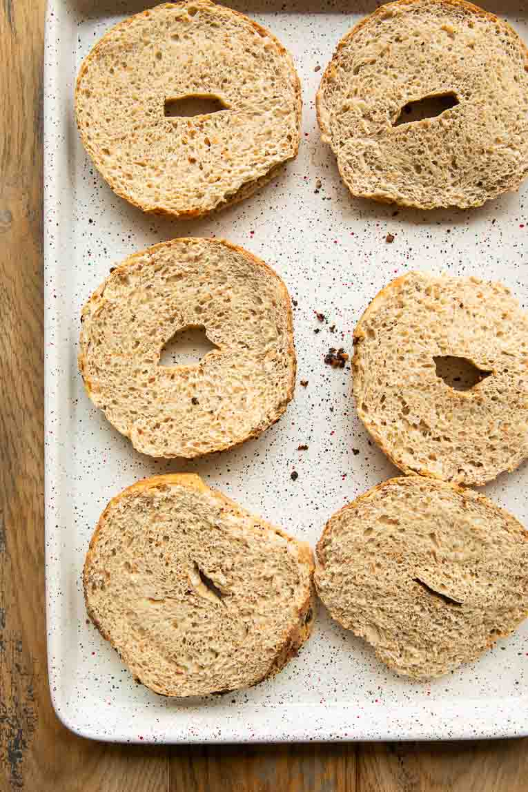 Bagels sliced on a baking sheet.