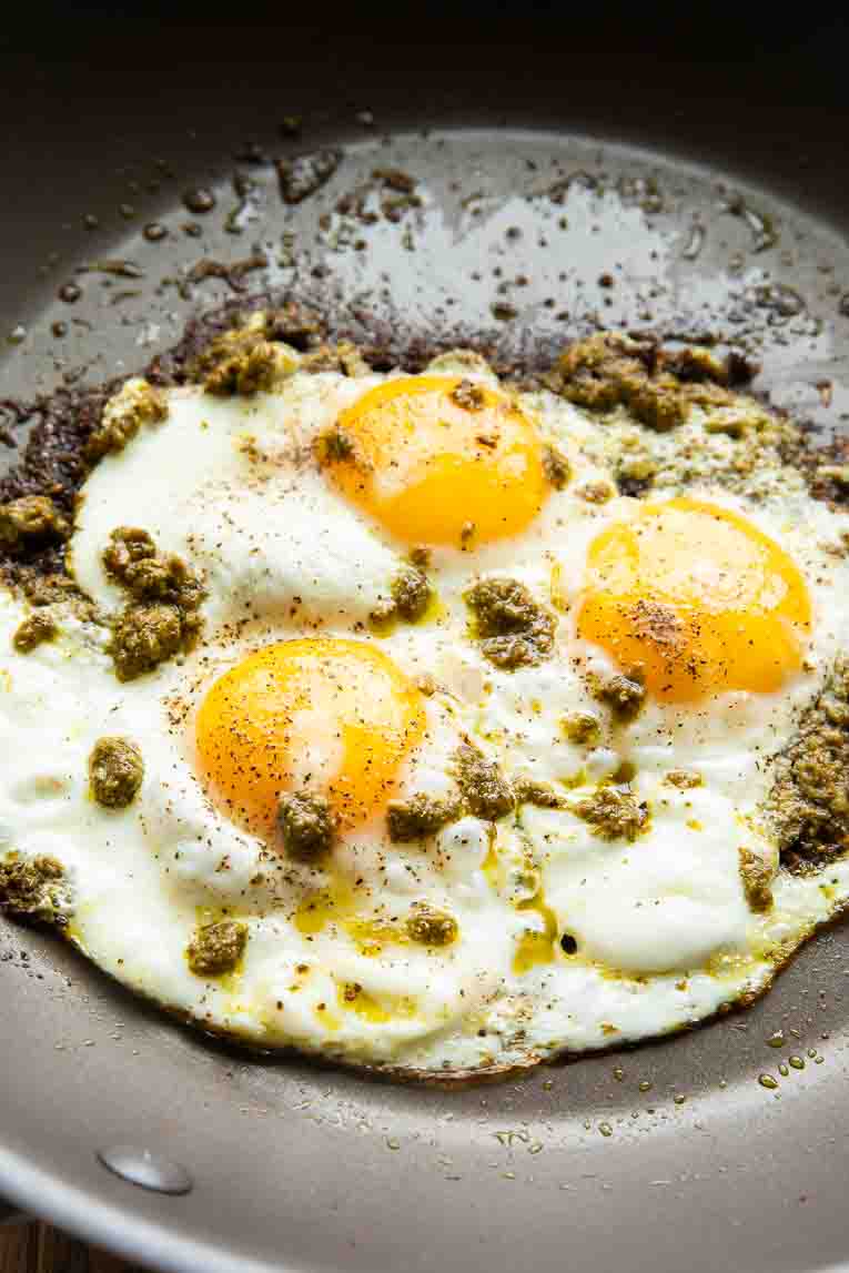 Pesto eggs being cooked in a skillet.