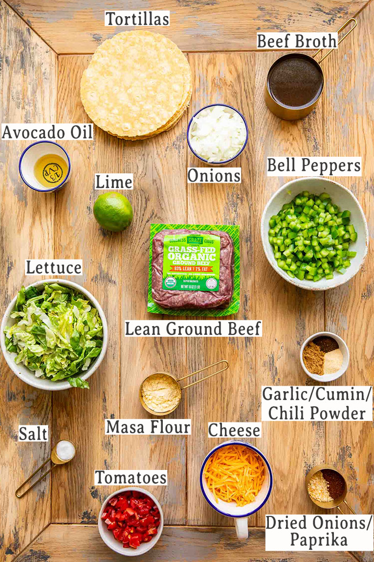 Ingredients for ground beef tacos on a wood table.