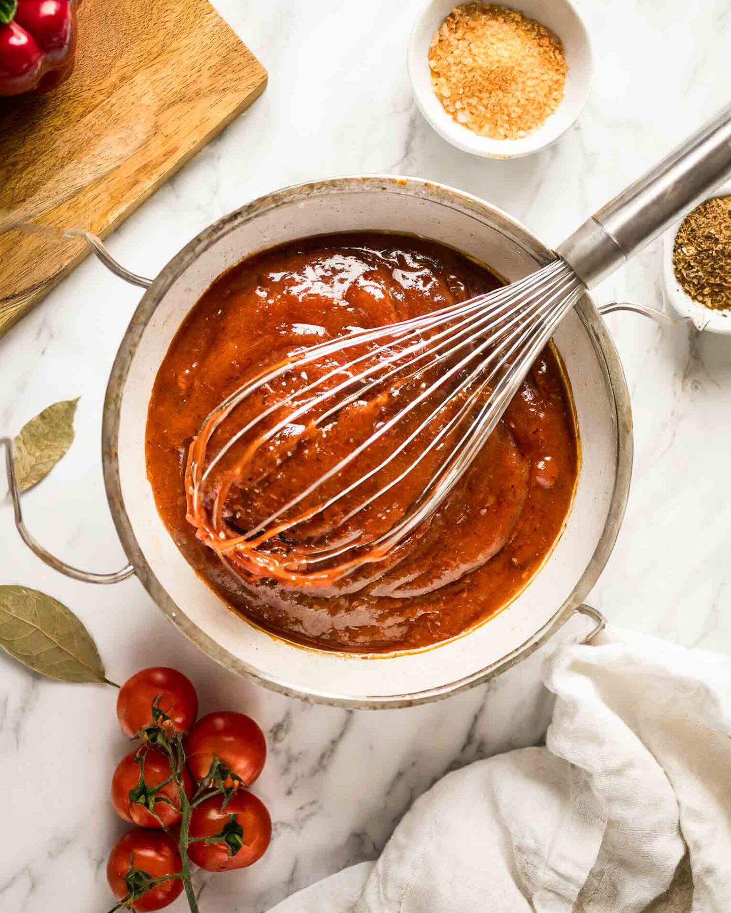 Homemade BBQ Sauce Recipe in a bowl with a whisk and ingredients.