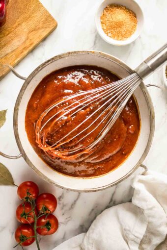 Homemade BBQ Sauce Recipe in a bowl with a whisk and ingredients.