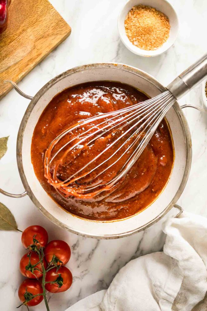 Homemade BBQ Sauce Recipe in a bowl with a whisk and ingredients.