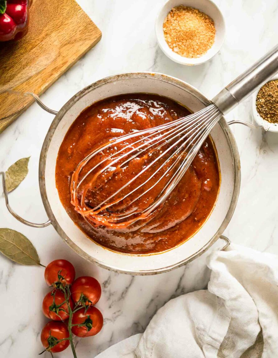 Homemade BBQ Sauce Recipe in a bowl with a whisk and ingredients.